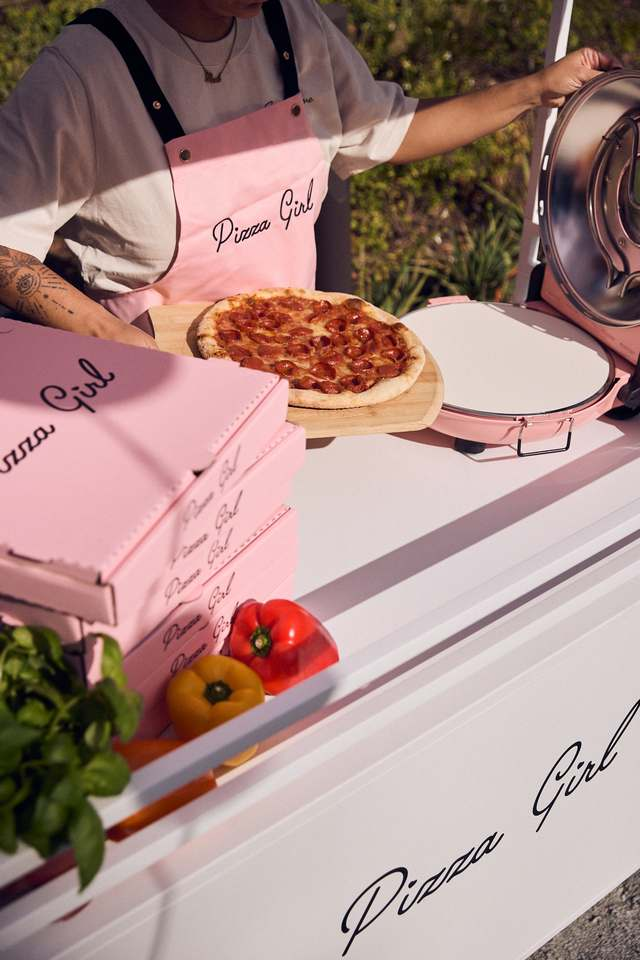 Staff member sliding a pepperoni pizza from the pink Pizza Girl oven