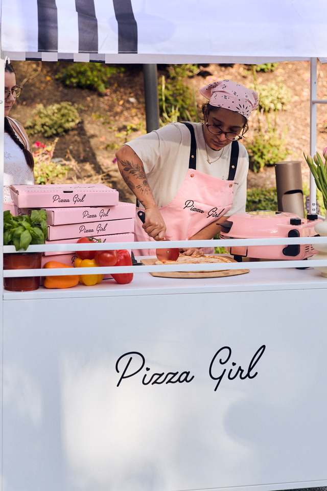 Pizza Girl team member slicing a fresh pizza at the cart